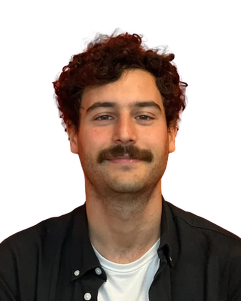 Alberto sorride, con baffi e capelli ricci.